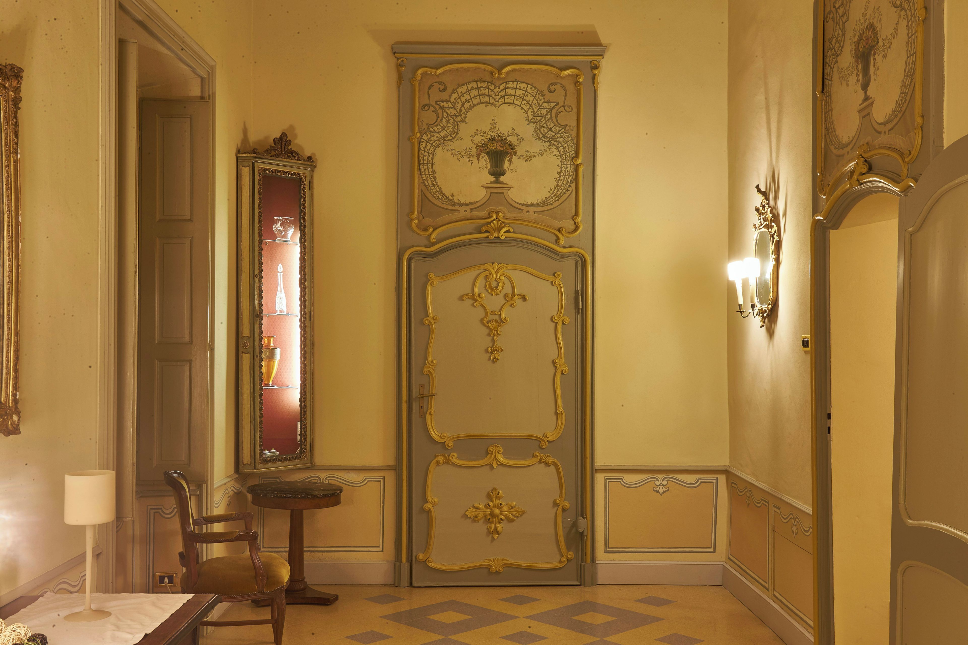 Une pièce dotée d’une grande porte richement décorée, d’un miroir, d’une petite table et d’une chaise.