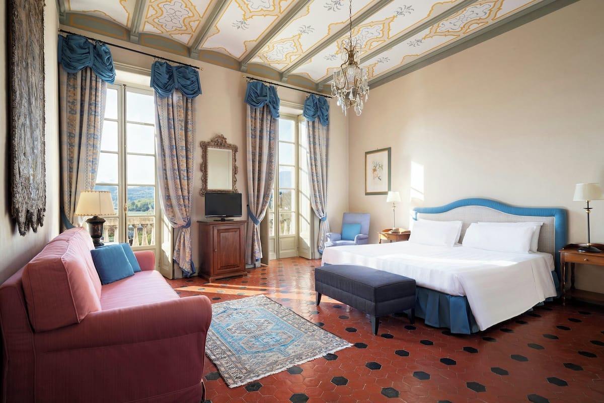 Ein Hotelzimmer mit einem großen Bett, einer Couch, einem Fernseher und Balkonblick.