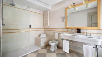 Un baño con ducha, bidé, dos lavamanos y un espejo grande.