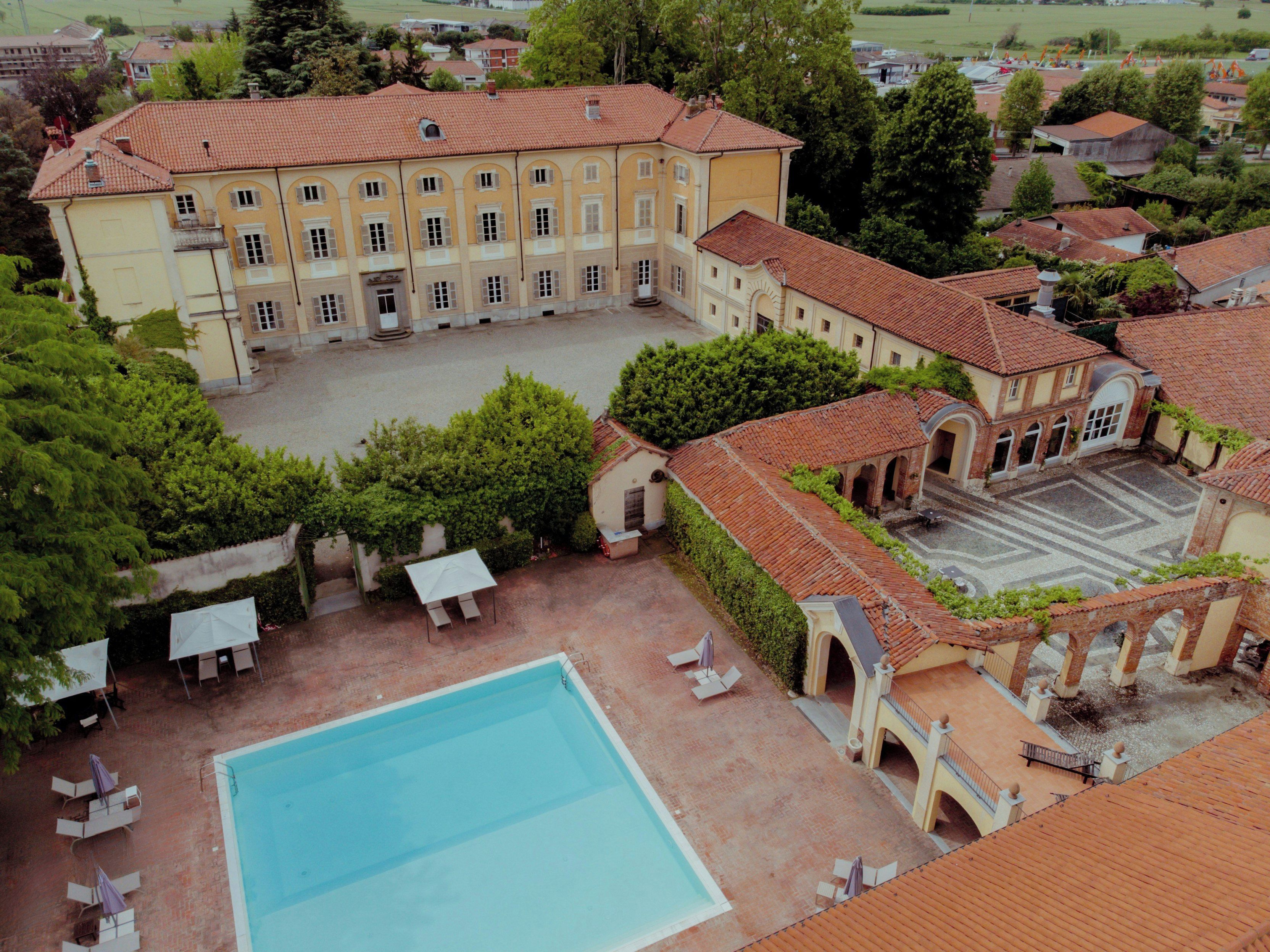 A large building with a courtyard, a swimming pool, and outdoor seating areas.