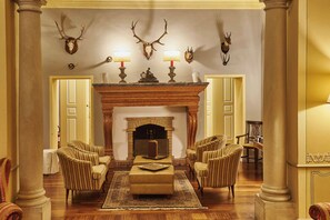 A formal living room with a fireplace, striped armchairs, and antler wall decorations. - Sina Villa Matilde (Romano Canavese)
