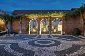 Un patio con suelo de piedra ornamentado, paredes de ladrillo y ventanas de arco.