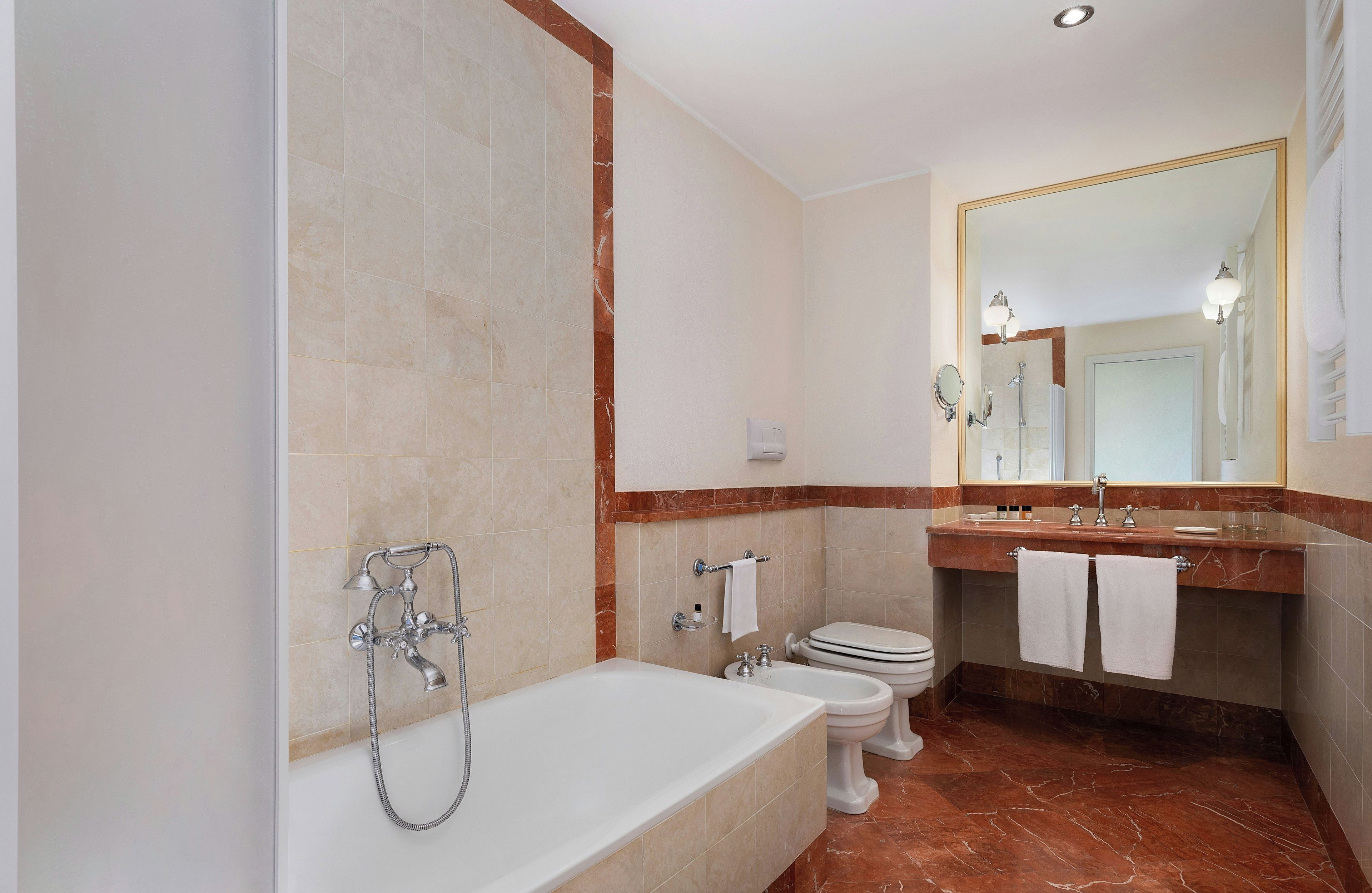 A bathroom with a bathtub, toilet, and sink with a large mirror.