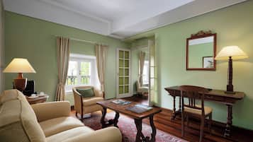 Una habitación con un sofá, una mesa de madera con una lámpara, una silla, un escritorio y un espejo en la pared.