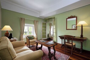 A room with a sofa, a wooden table with a lamp, a chair, a desk, and a mirror on the wall. - Sina Villa Matilde (Romano Canavese)