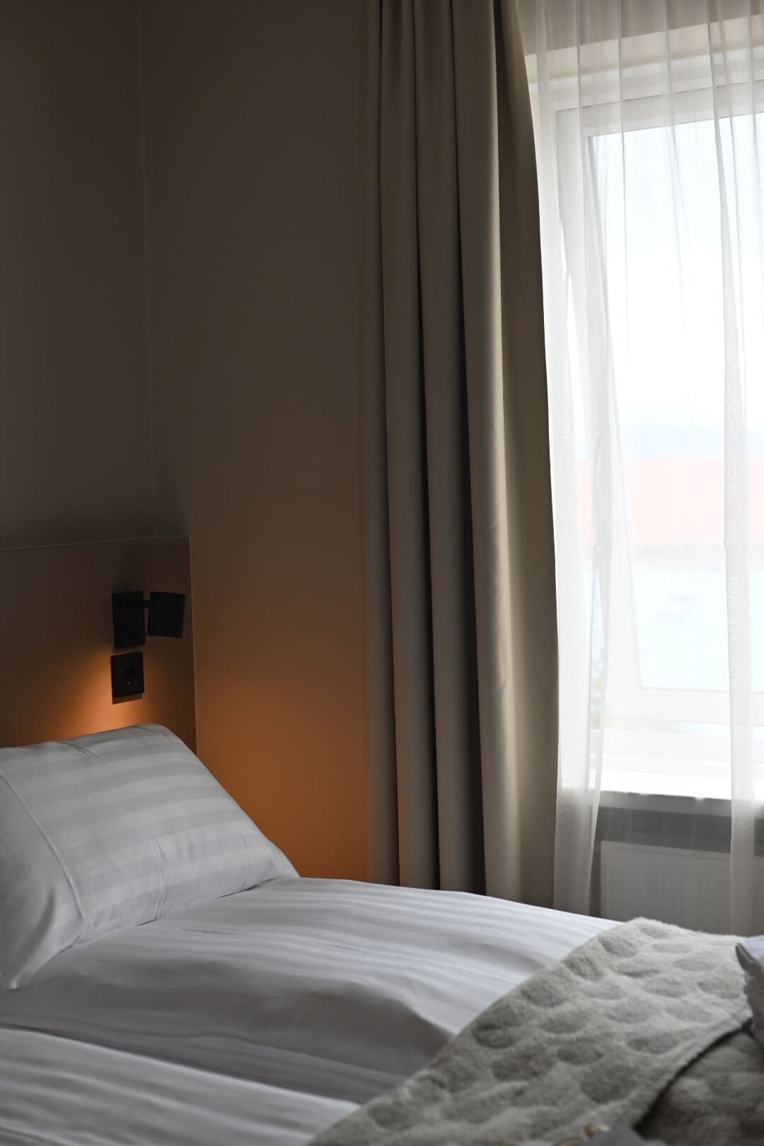 Une chambre d’hôtel avec un lit, des rideaux et une fenêtre donnant sur un beau paysage.