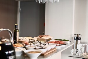 Una mesa de buffet con diversos alimentos y una botella de vino.