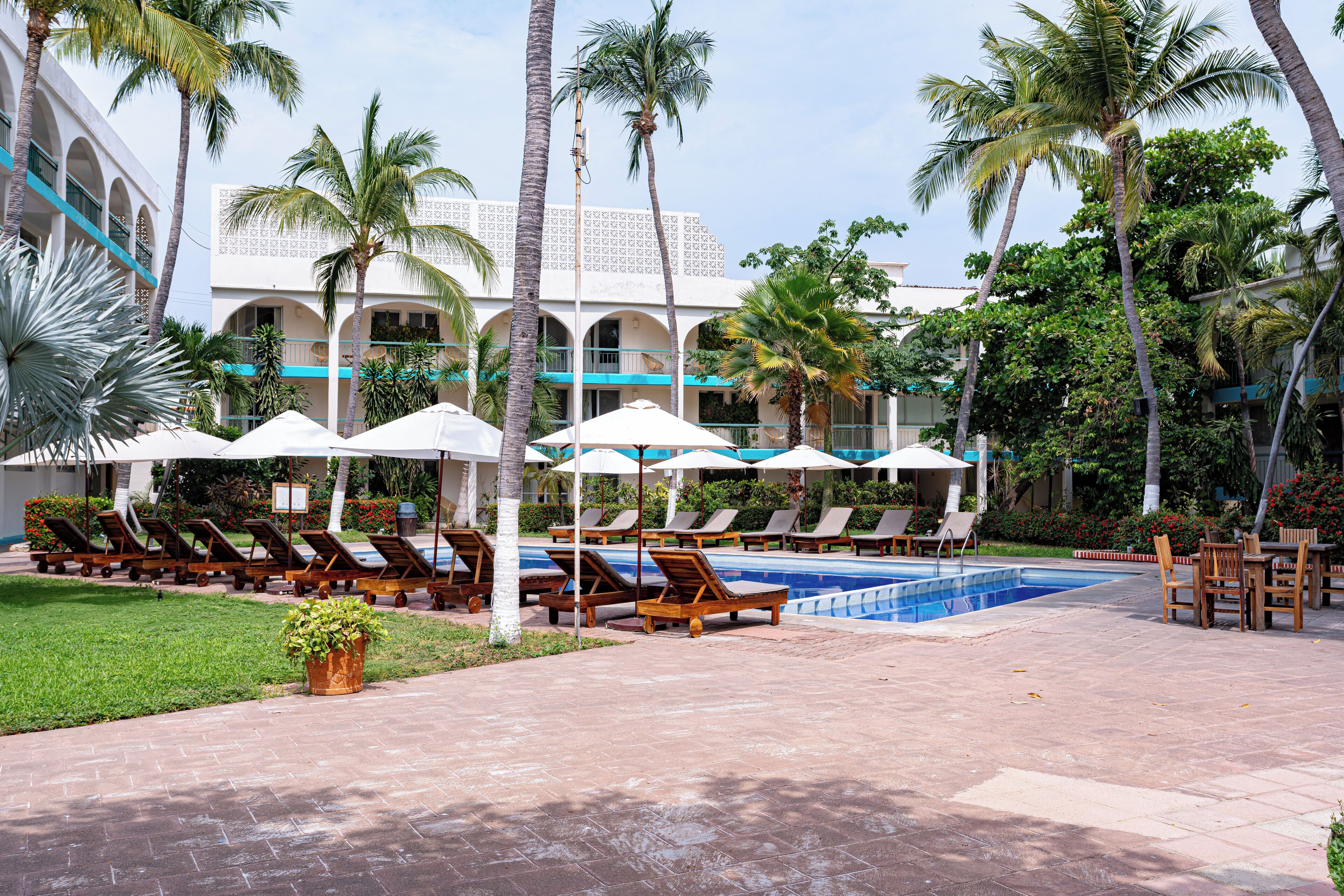 Una piscina al aire libre, sombrillas, sillones reclinables de piscina