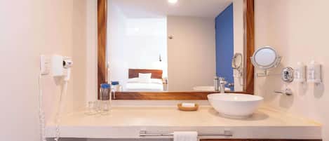 A hotel bathroom with a large mirror, a sink, a towel rack, and a telephone.