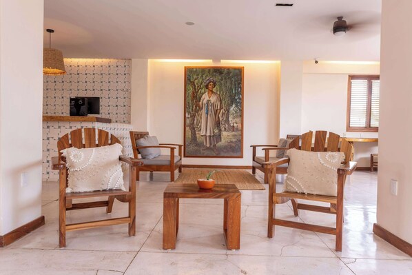 Una sala de estar con sillas de madera, una mesa de centro y un cuadro en la pared.