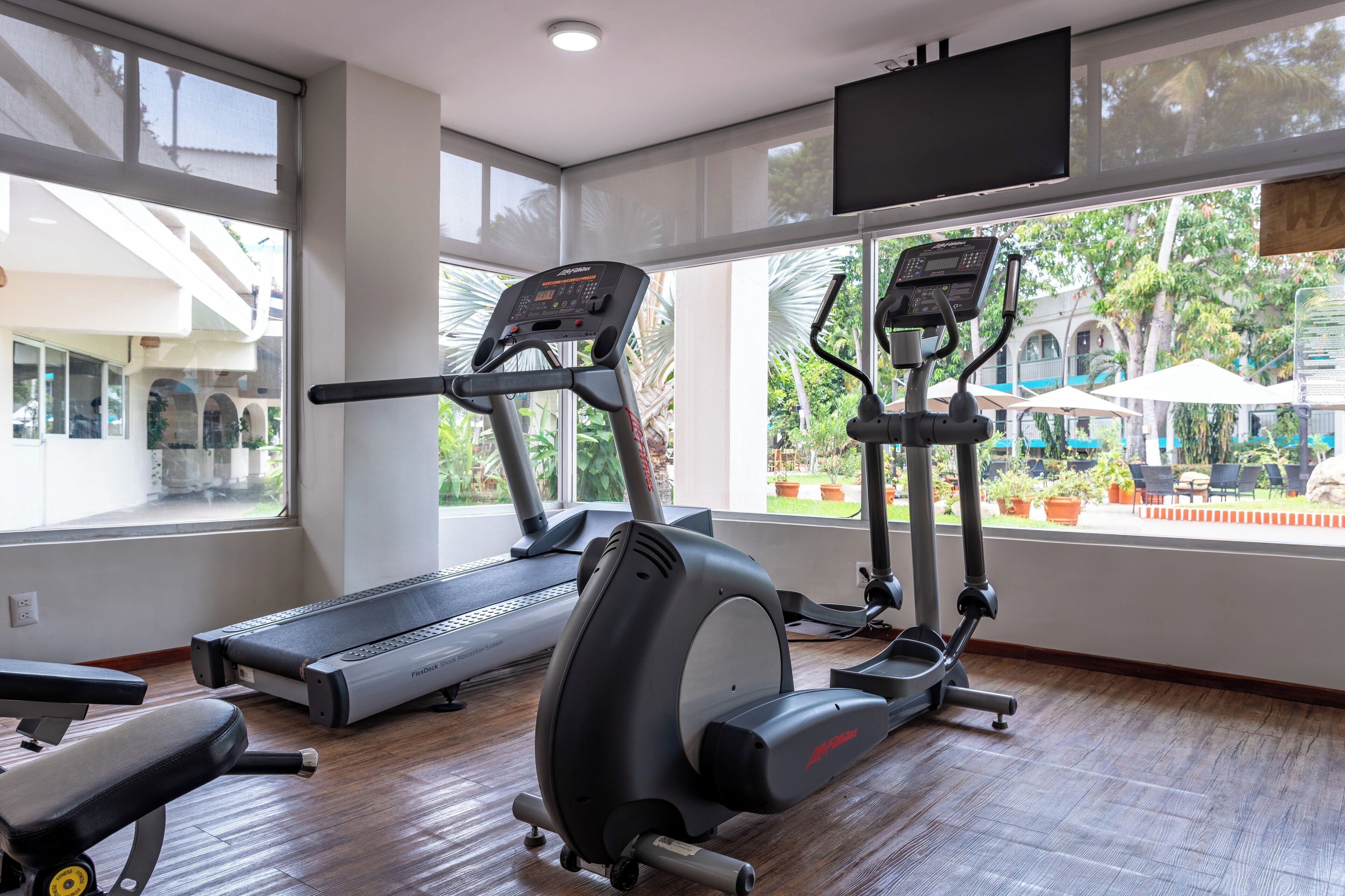 A gym with treadmills, an elliptical, and a bench.