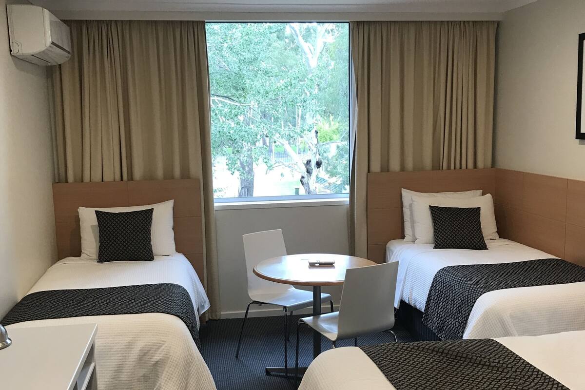 A hotel room with two beds, a small round table, and a chair.
