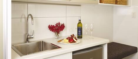 Una cocina moderna con un lavamanos de acero inoxidable, una botella de vino y una copa de vino sobre la encimera.