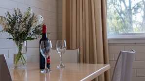 Una mesa de comedor con dos sillas, una botella de vino y dos copas de vino.