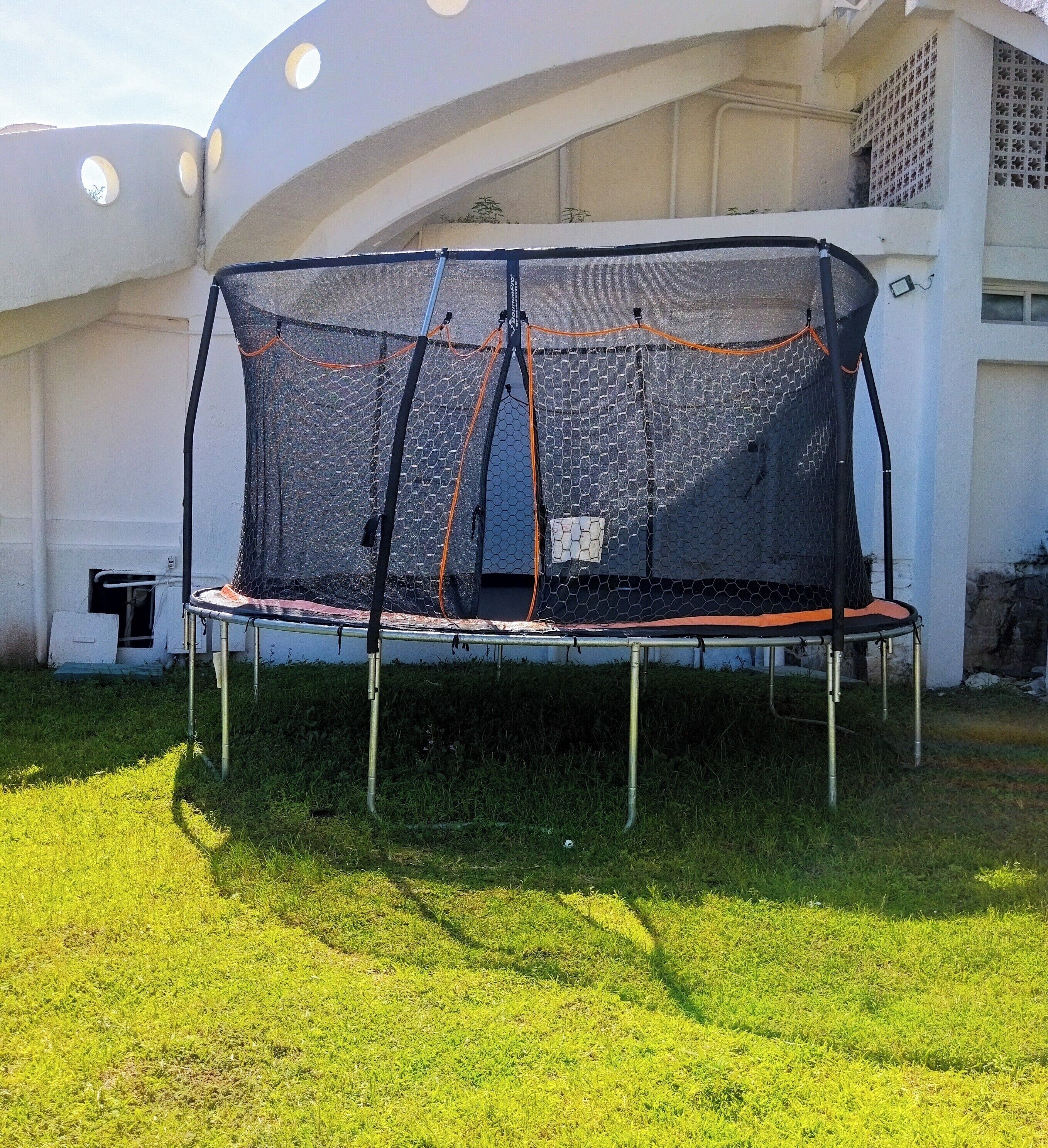 A trampoline with a safety net in a grassy area.