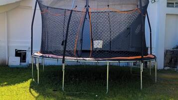 A trampoline with a safety net in a grassy area.