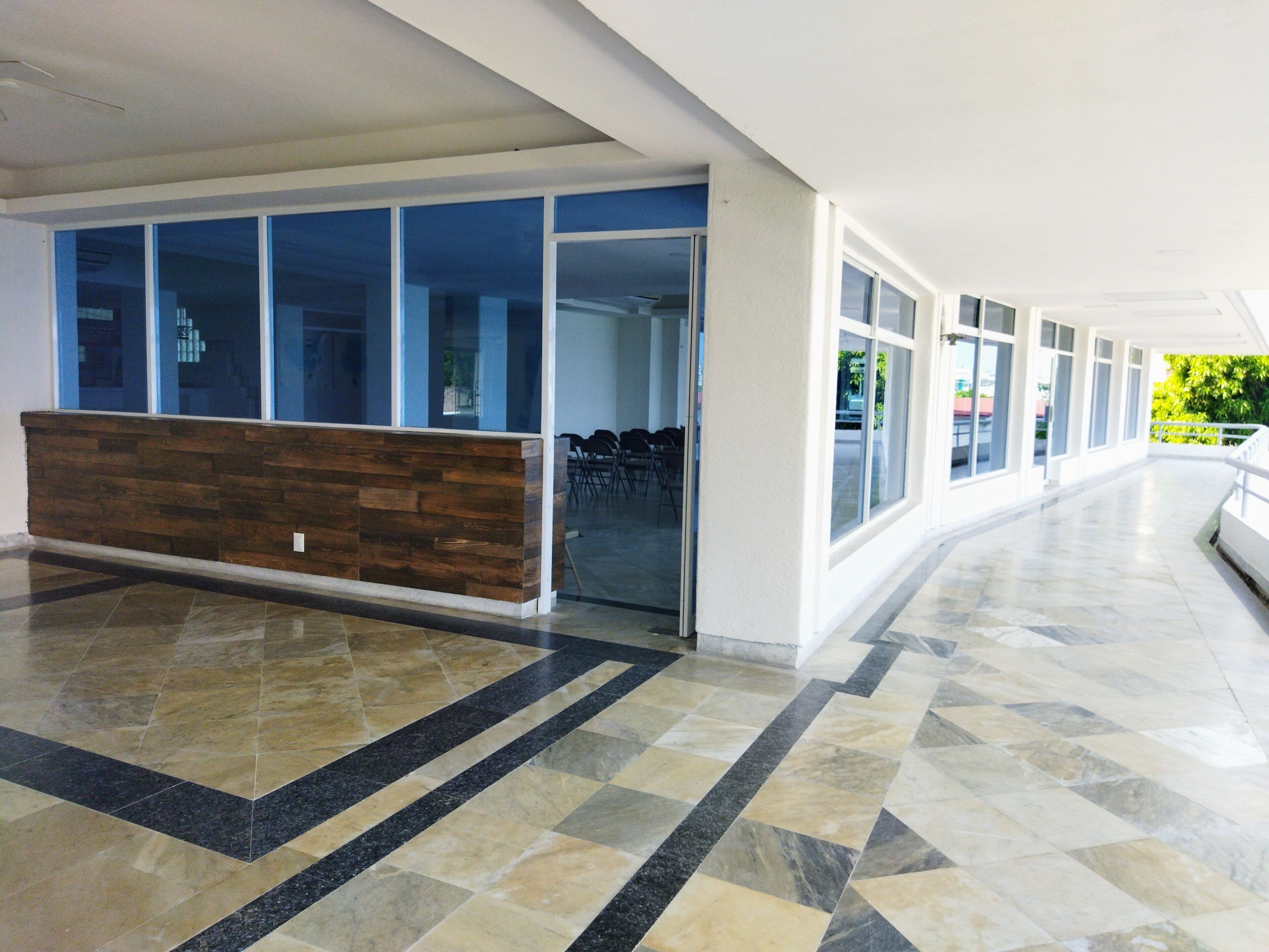 A spacious lobby with a reception desk, large windows, and a tiled floor.