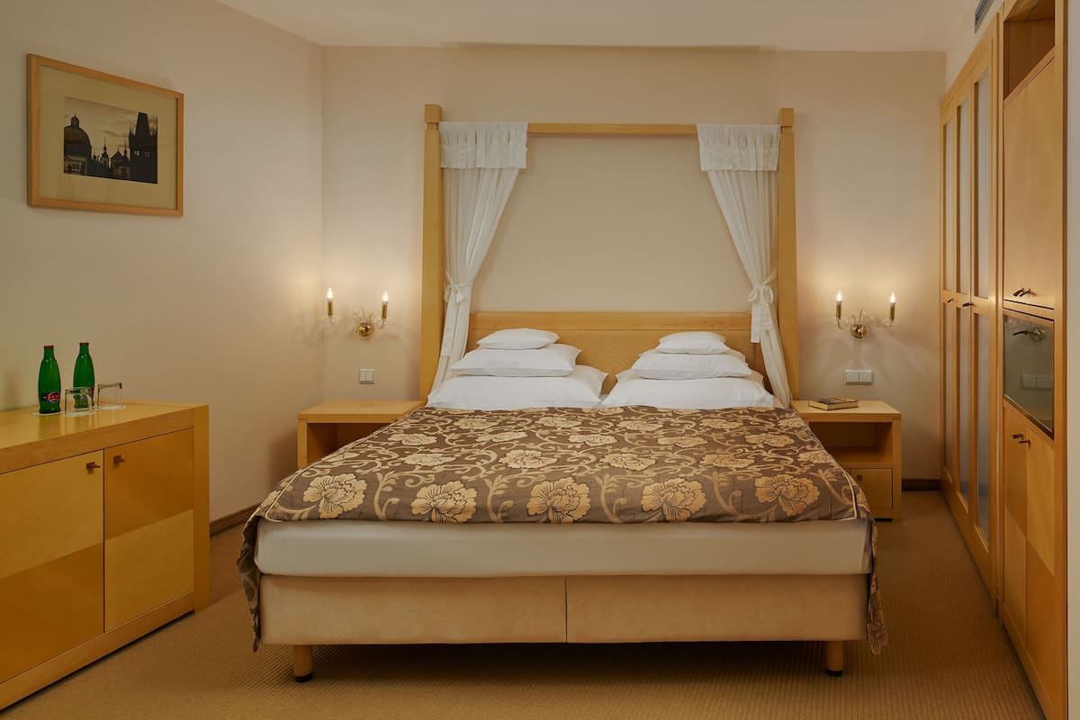 Un dormitorio ordenado con cama, mesitas de noche, armario y un cuadro en la pared.