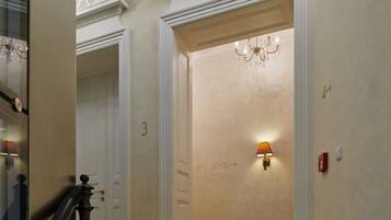 A grand hallway with a chandelier, a staircase, and a wall with a number sequence.
