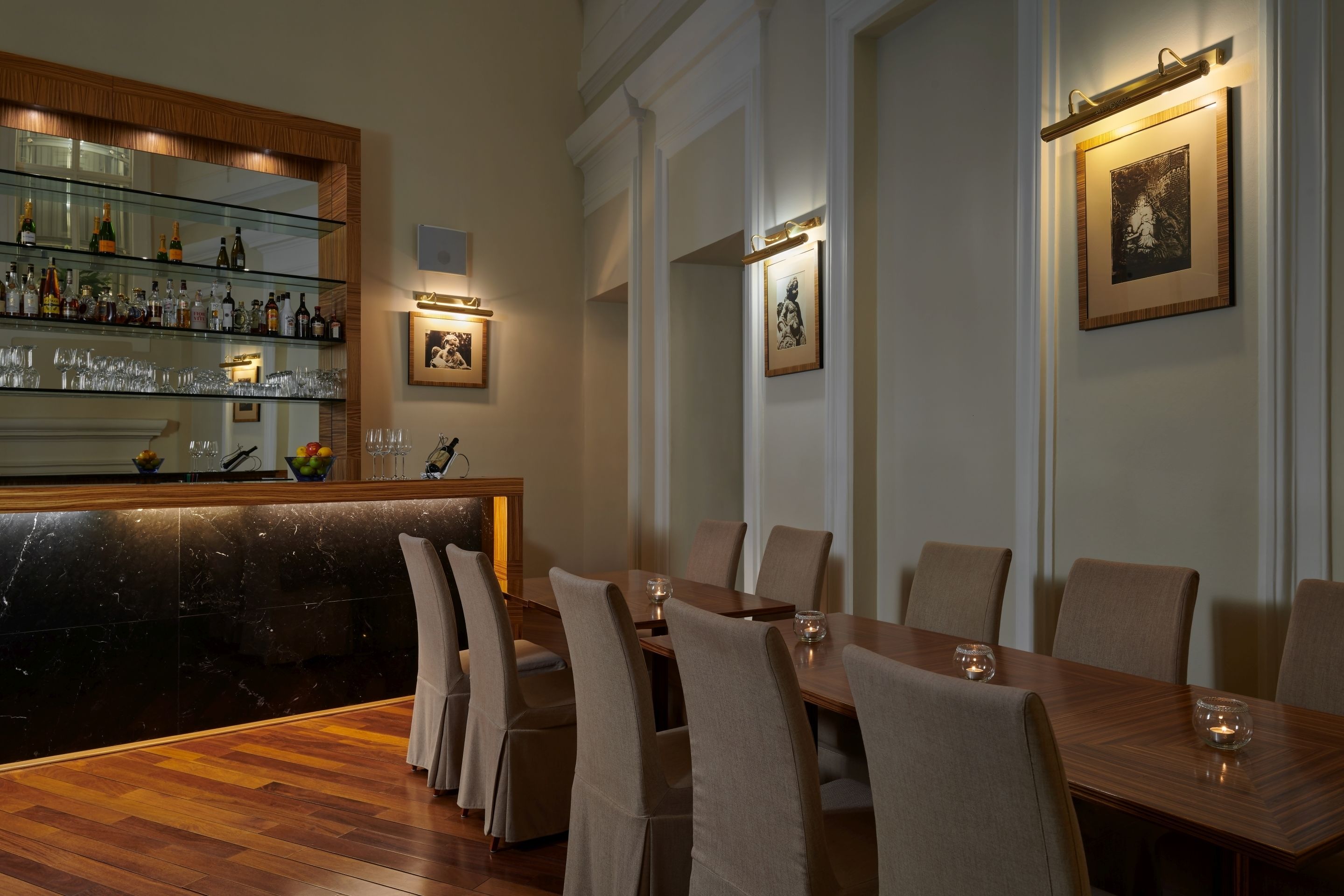 A dining area with a long wooden table, six chairs, and a bar with a glass display case.