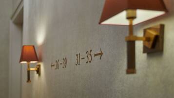 A hallway with directional signs and wall-mounted lamps.
