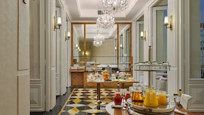 A hotel lobby with a checkered floor, a buffet with breakfast items, and a chandelier. - Ventana Hotel Prague (Prague)