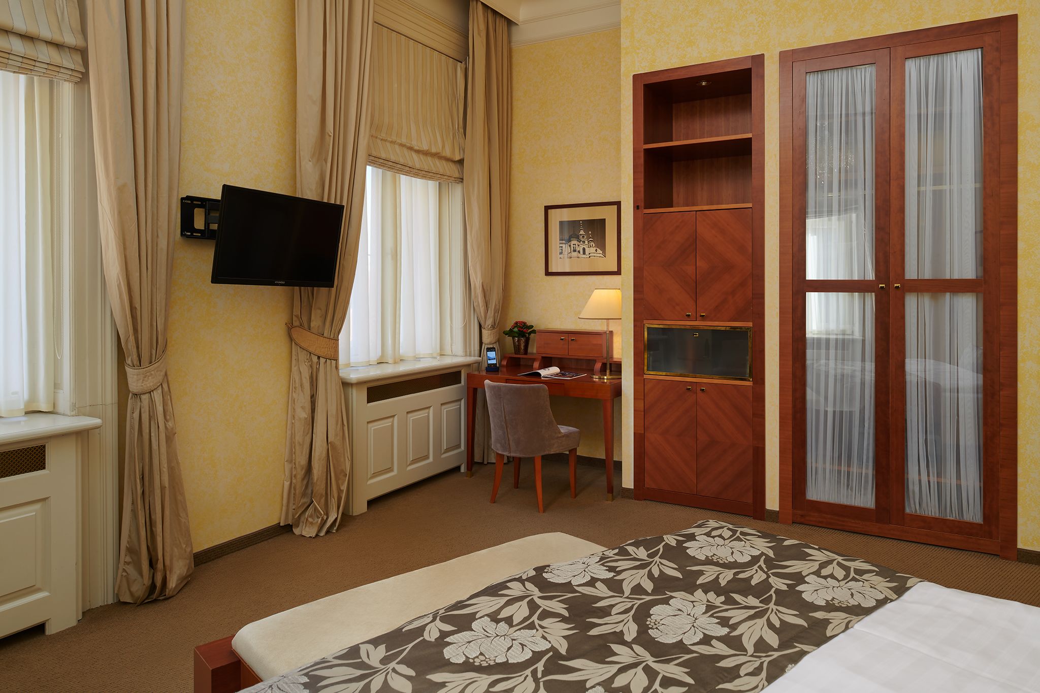 Una camera d'albergo con un letto, una scrivania, una sedia, un televisore e un armadio.