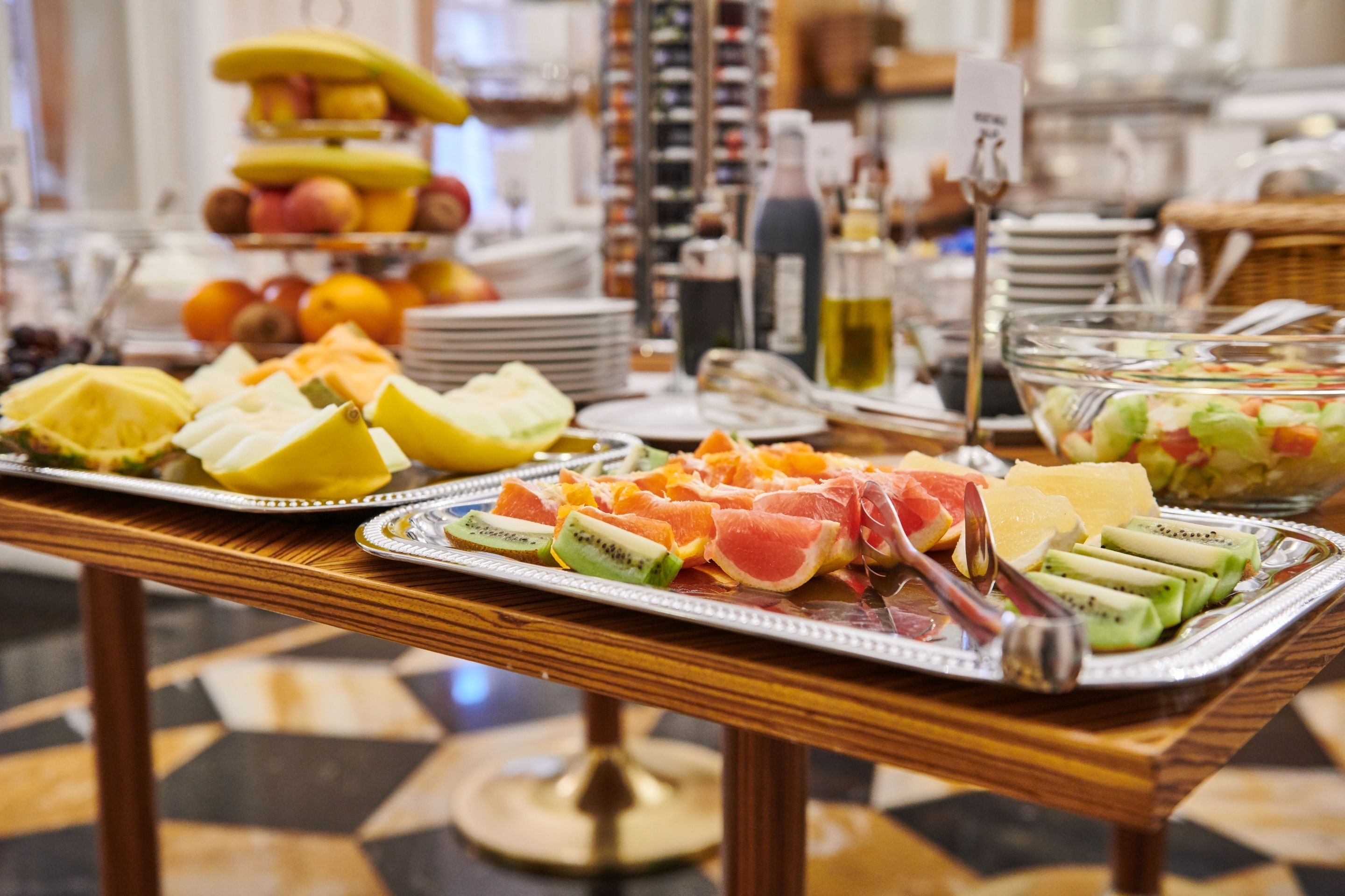 Una mesa de bufé con diversas frutas y una ensalada.