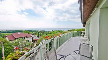 A balcony with a view of the sea, a railing, and a table with chairs.