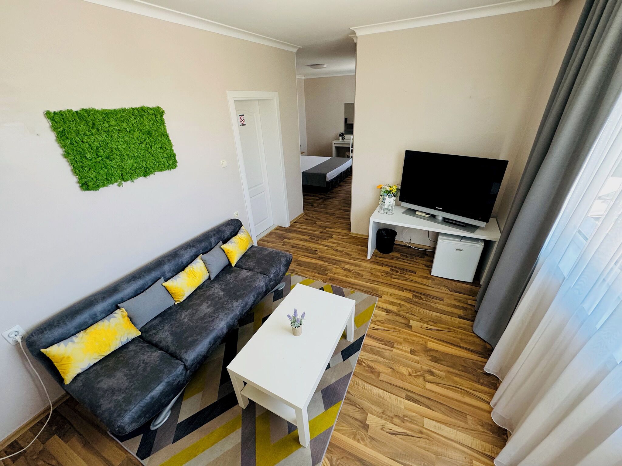 Una sala de estar moderna con un sofá gris, una mesa de centro blanca y un televisor de pantalla plana sobre un mueble blanco.