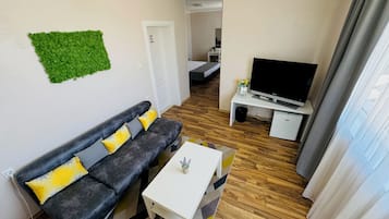 Una sala de estar moderna con un sofá gris, una mesa de centro blanca y un televisor de pantalla plana sobre un mueble blanco.