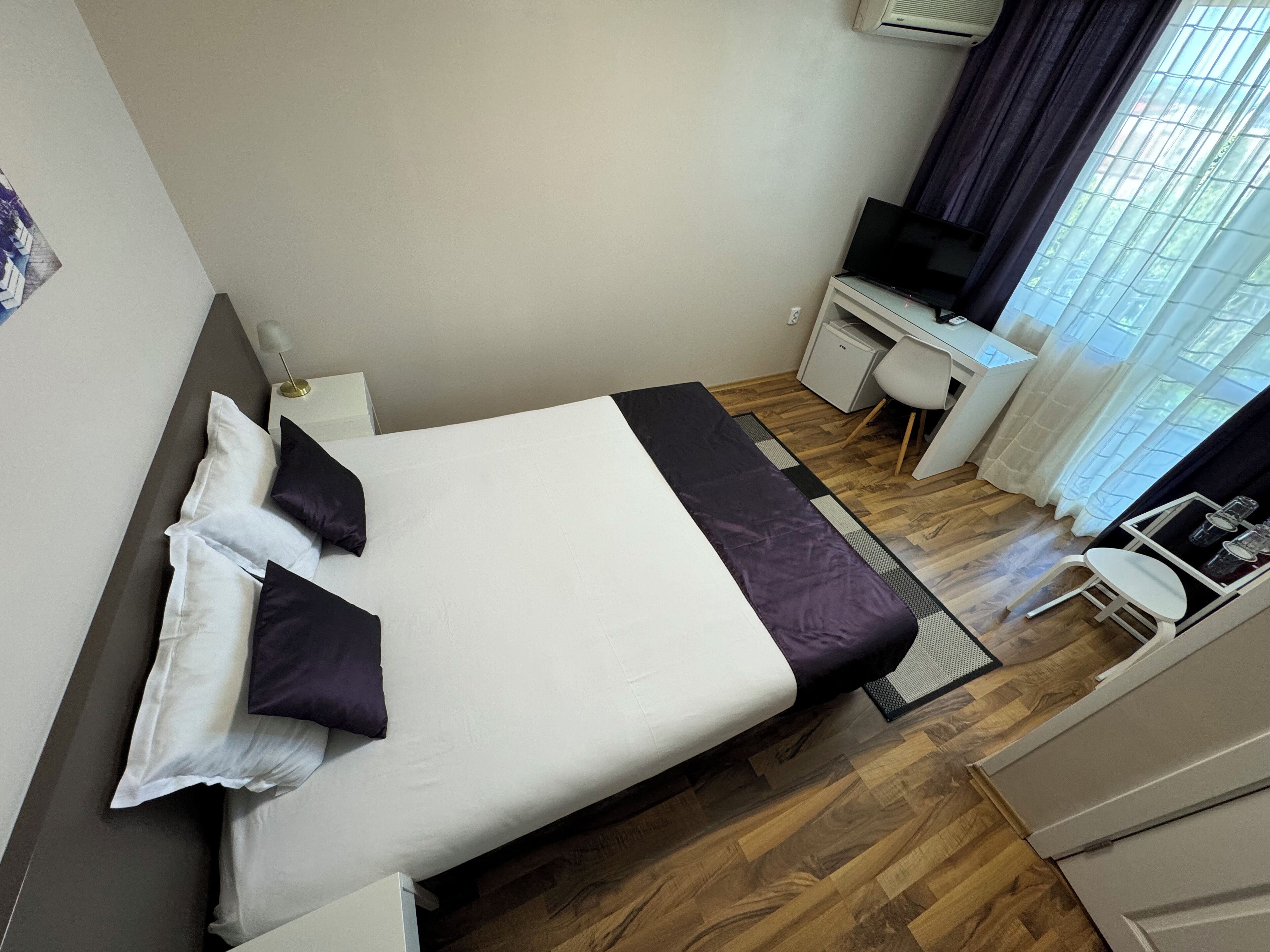 Ein ordentlich eingerichtetes Hotelzimmer mit Bett, Schreibtisch, Stuhl und Fernseher.