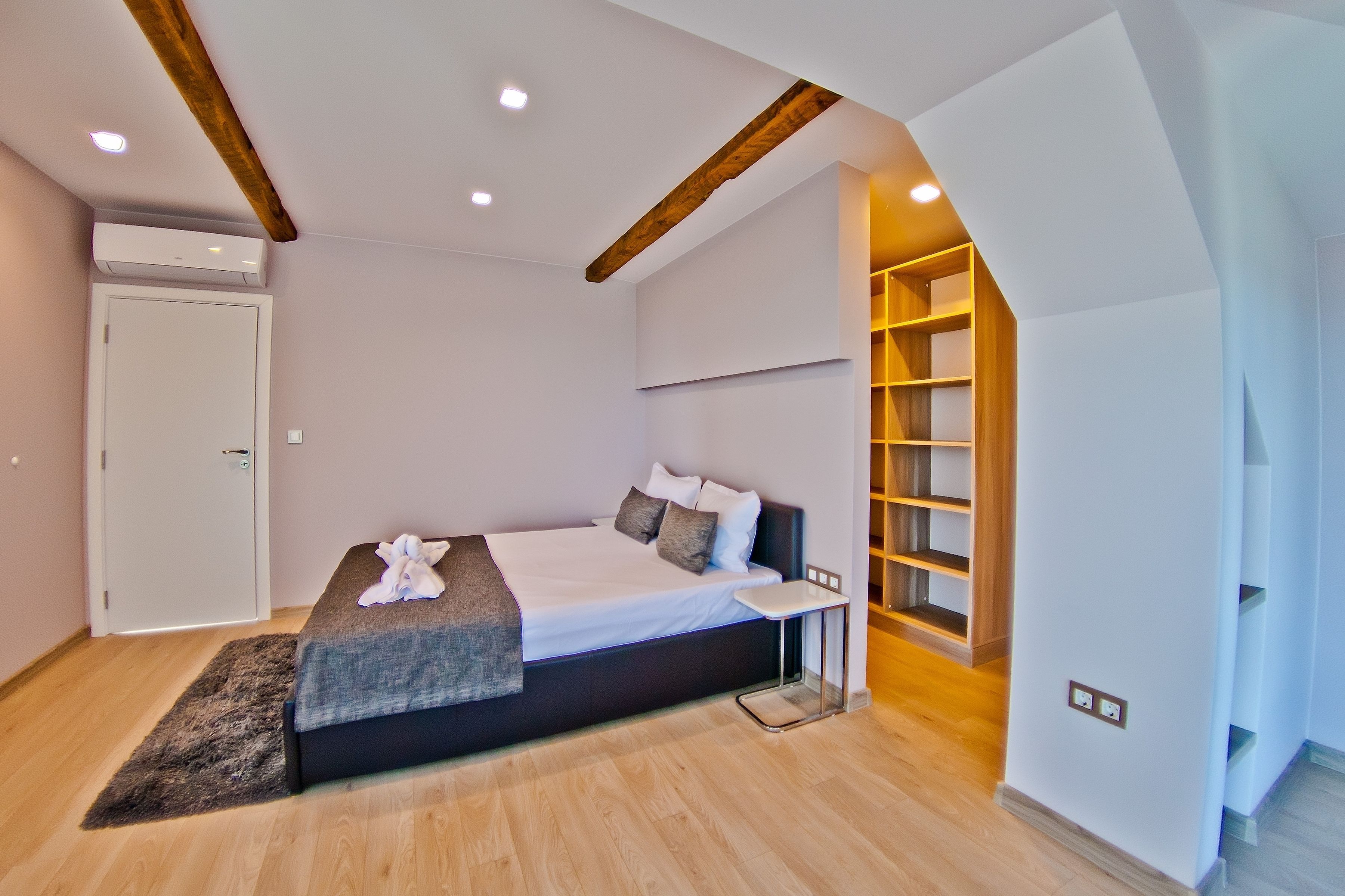 Un dormitorio moderno con cama, mesita de noche y estanterías empotradas.