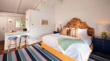 A bedroom with a bed, a desk, and two stools.