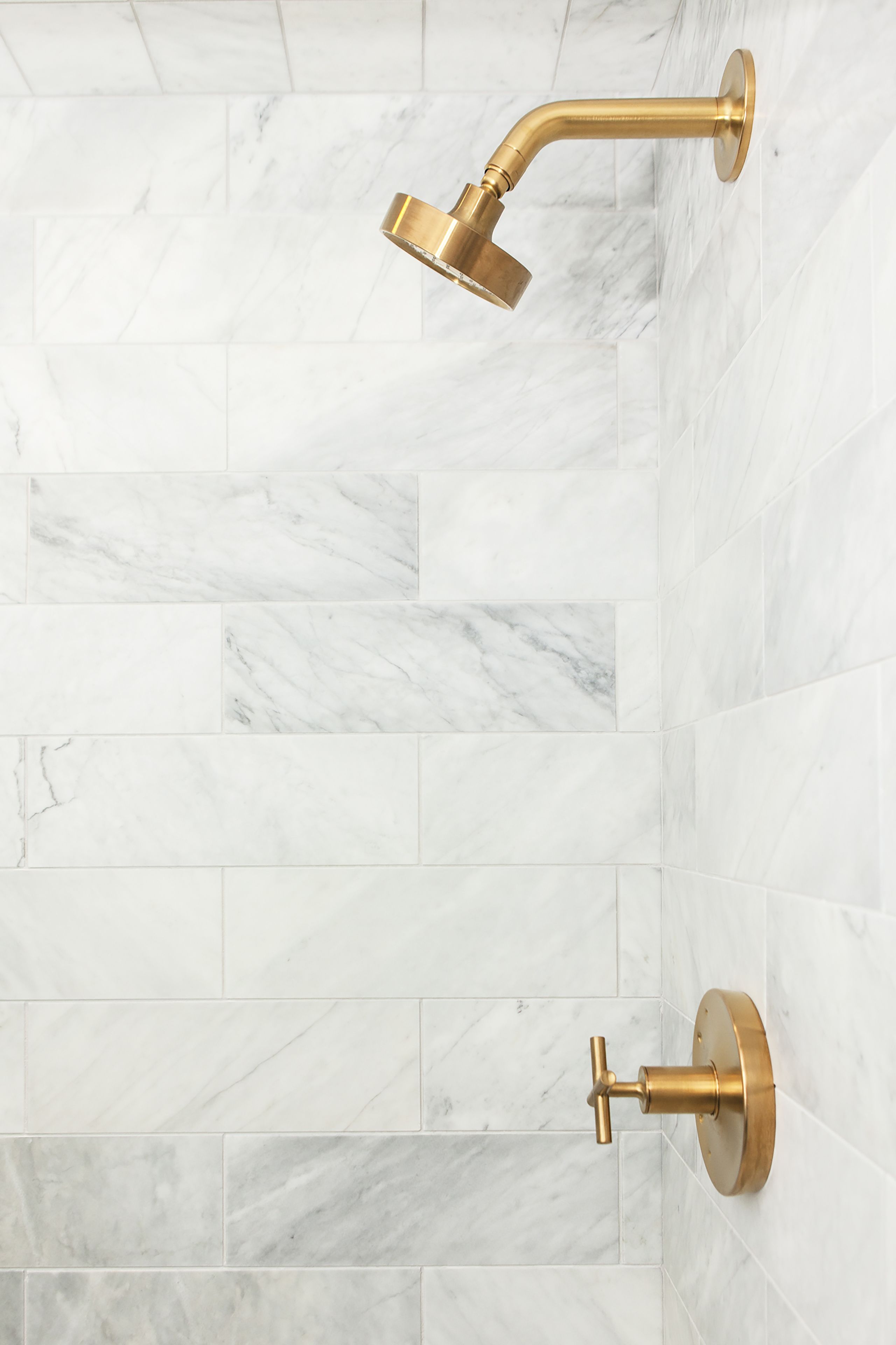 Une salle de bain aux carreaux de marbre blanc et aux accessoires dorés.