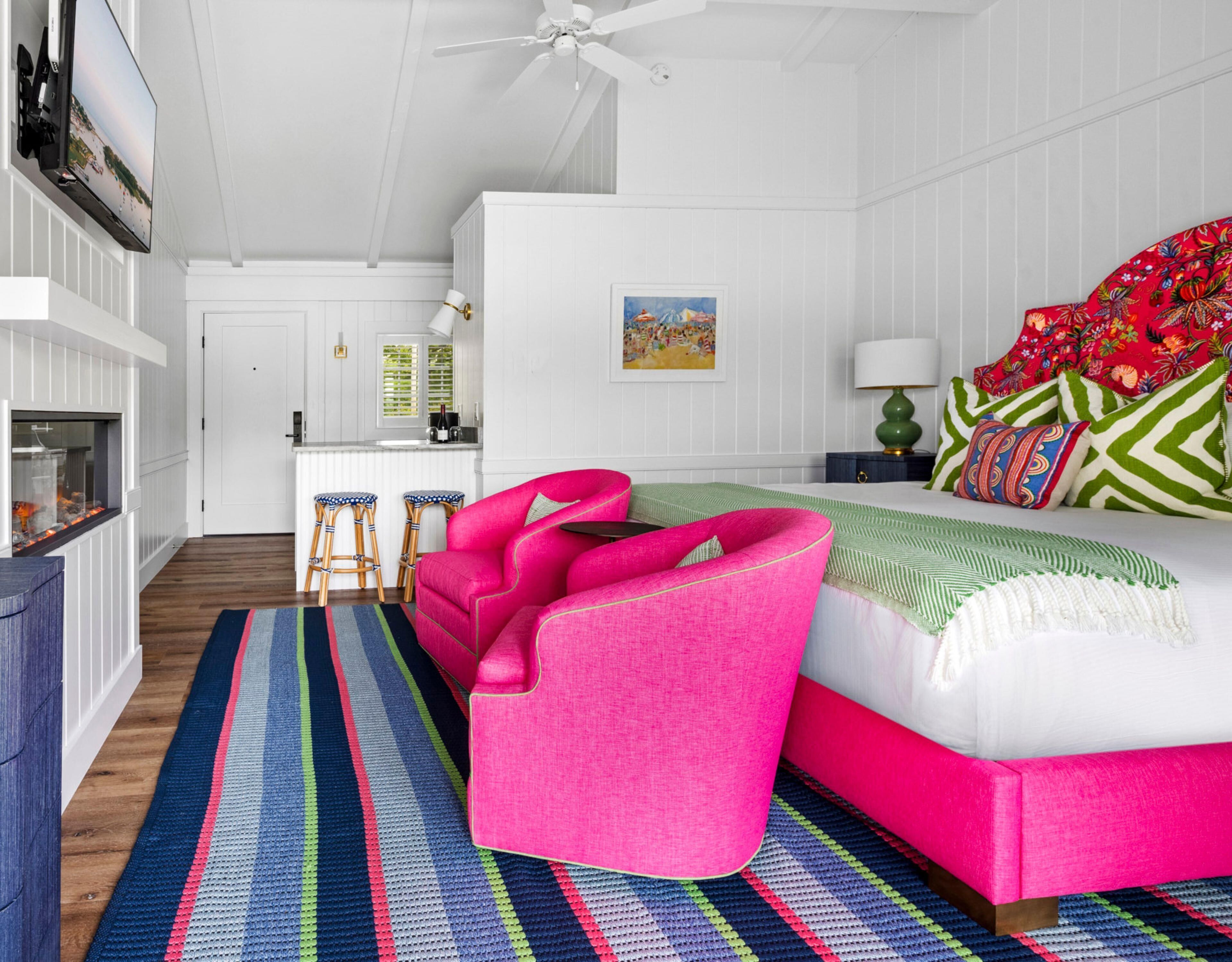 A bedroom with a bed, a chair, a desk, a window, and a ceiling fan.