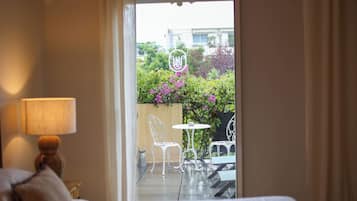 Una camera d'albergo con un letto, una lampada e vista su un patio esterno con sedie e un tavolo.