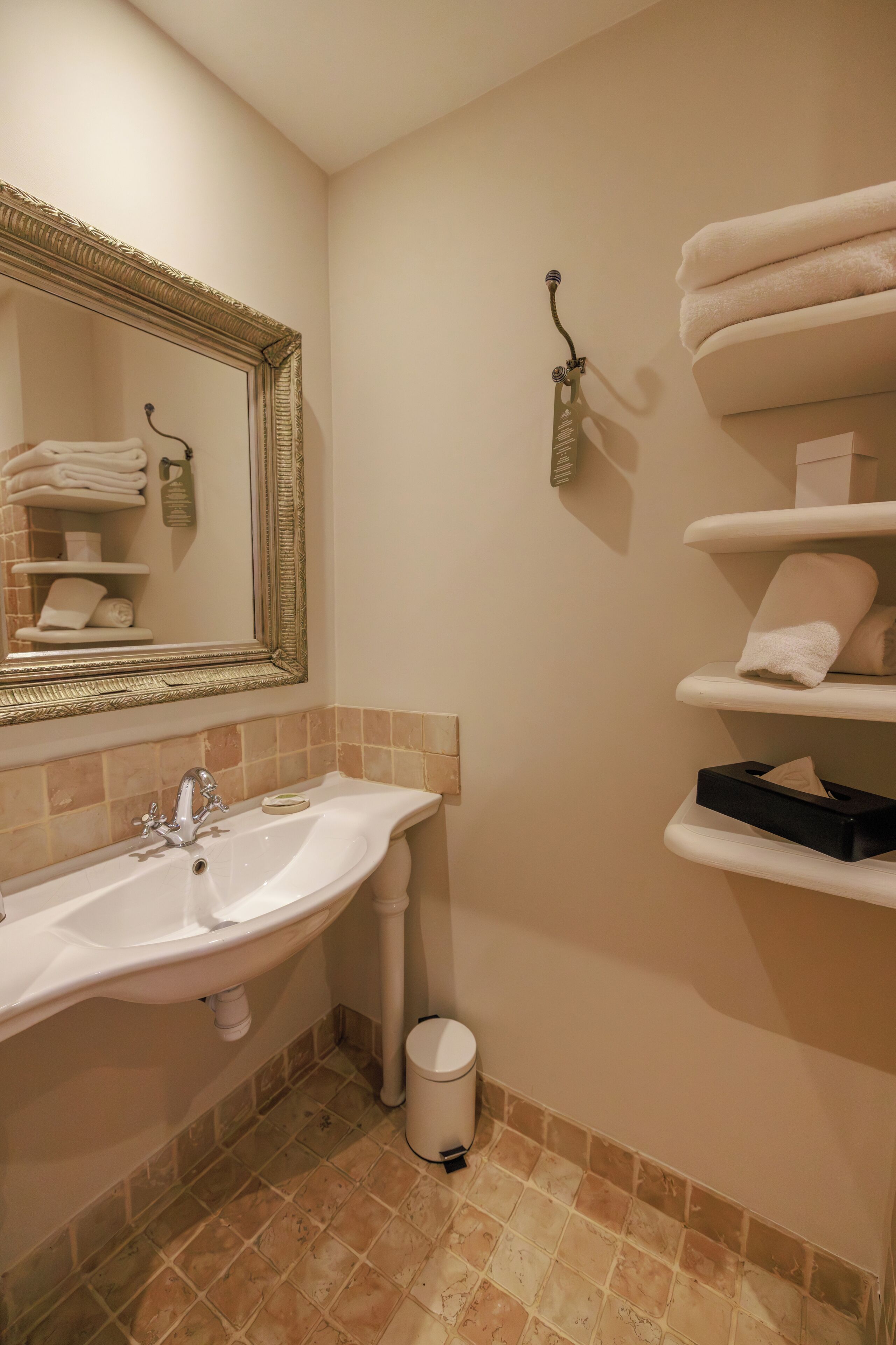 Une salle de bain équipée d’un lavabo, d’un miroir, d’un porte-serviettes et d’étagères pour les serviettes.