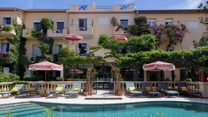 A pool area with sun loungers and umbrellas, surrounded by a building with balconies and plants. - Hôtel La Villa Sainte Valérie Adults Only (Antibes)