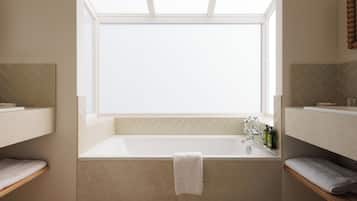 Ein modernes Badezimmer mit einer freistehenden Badewanne, einem Oberlicht und einem Spiegel über der Wanne.