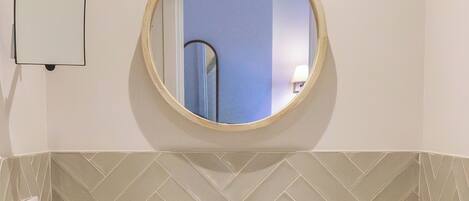 A bathroom with a round mirror, a sink, and a towel rack.