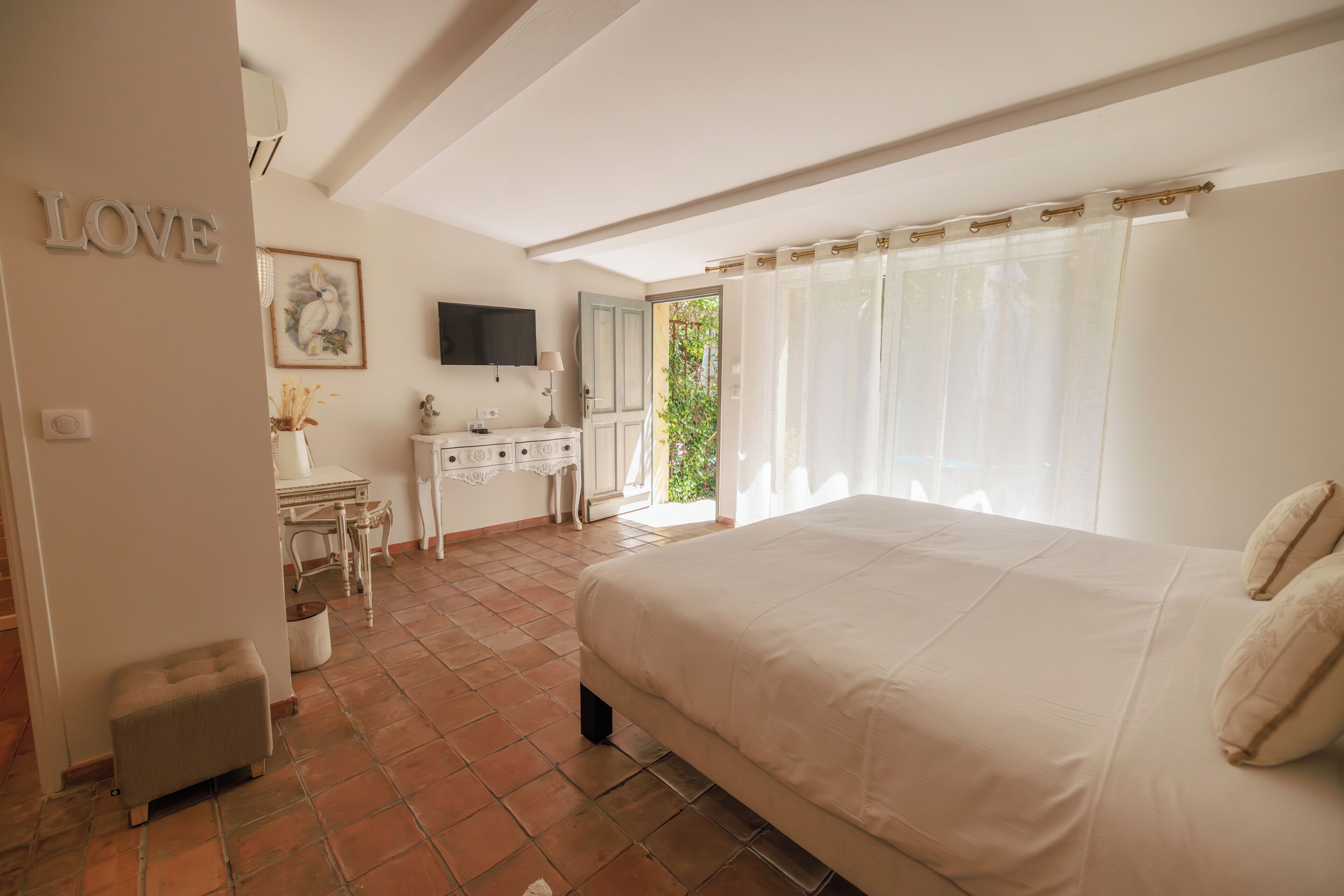 Une chambre à coucher avec un lit, un bureau, une chaise, un téléviseur et une fenêtre avec des rideaux.