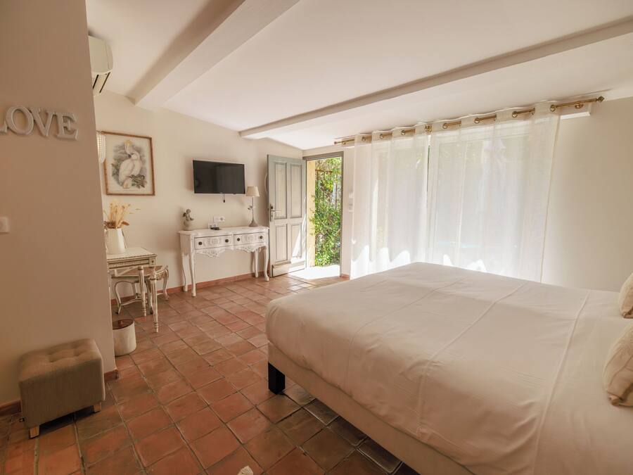 Une chambre à coucher avec un lit, un bureau, une chaise, un téléviseur et une fenêtre avec des rideaux.