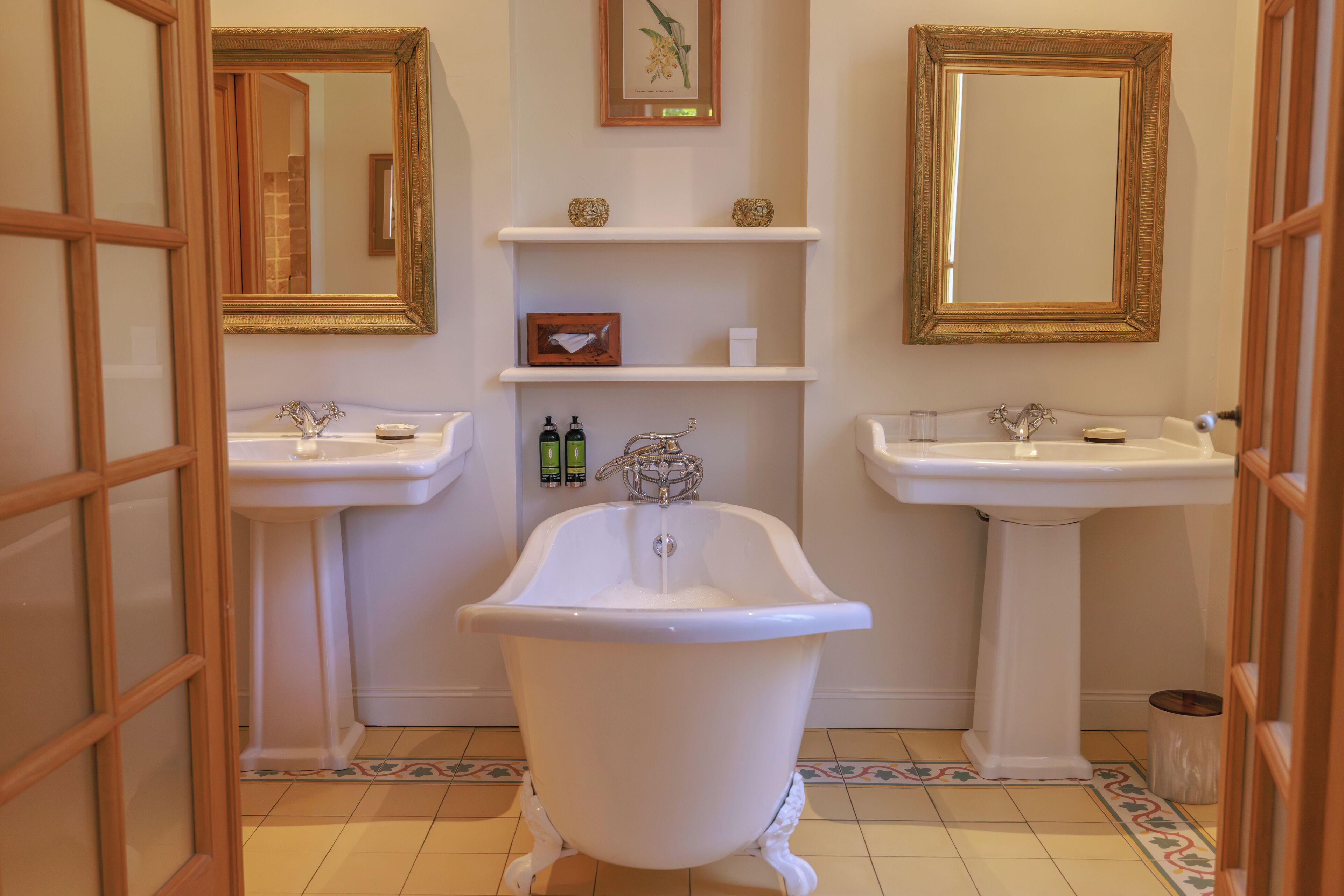 A bathroom with a clawfoot bathtub, two sinks, and a mirror.