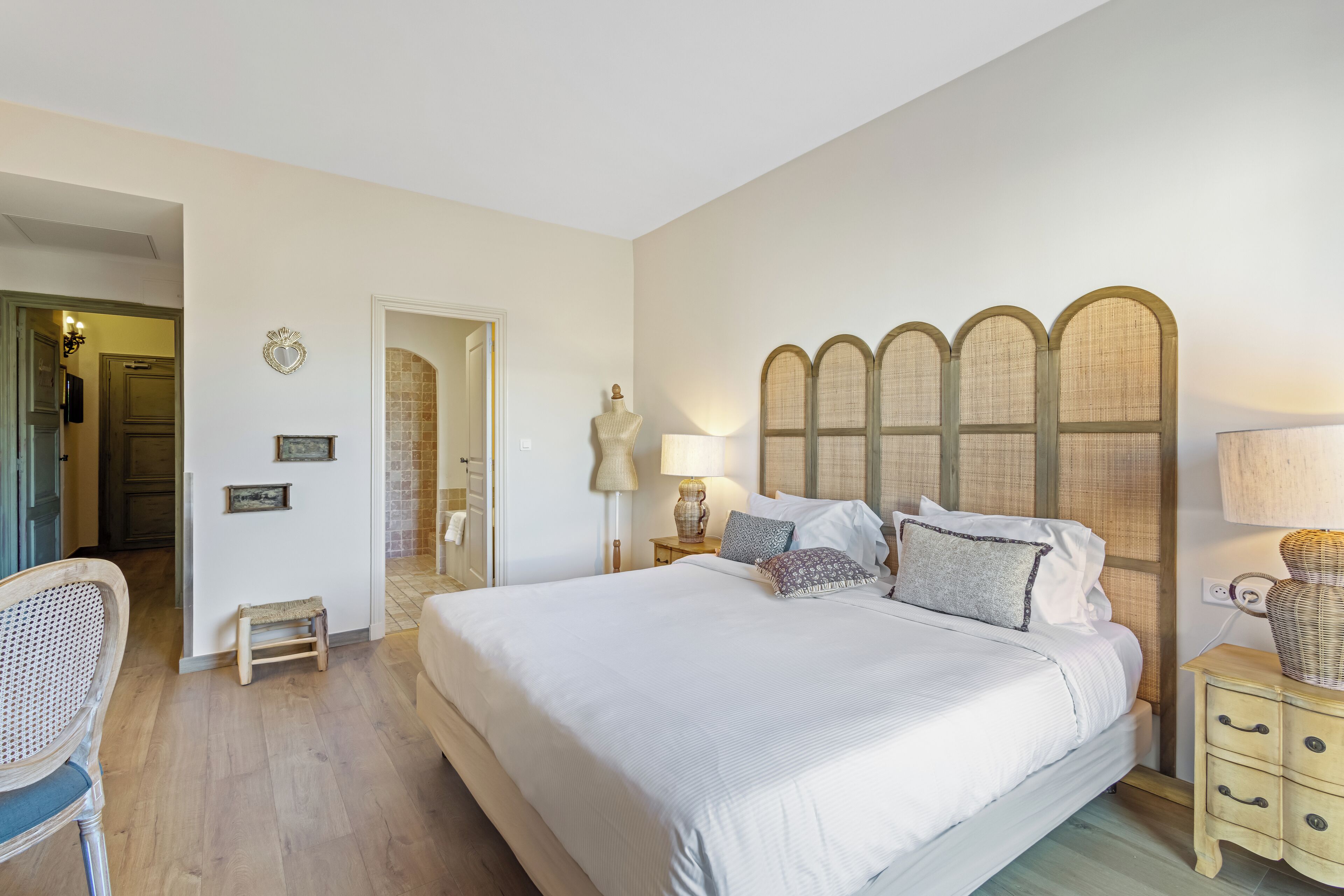 A neatly arranged bedroom with a large bed, bedside tables, a chair, and a wardrobe.
