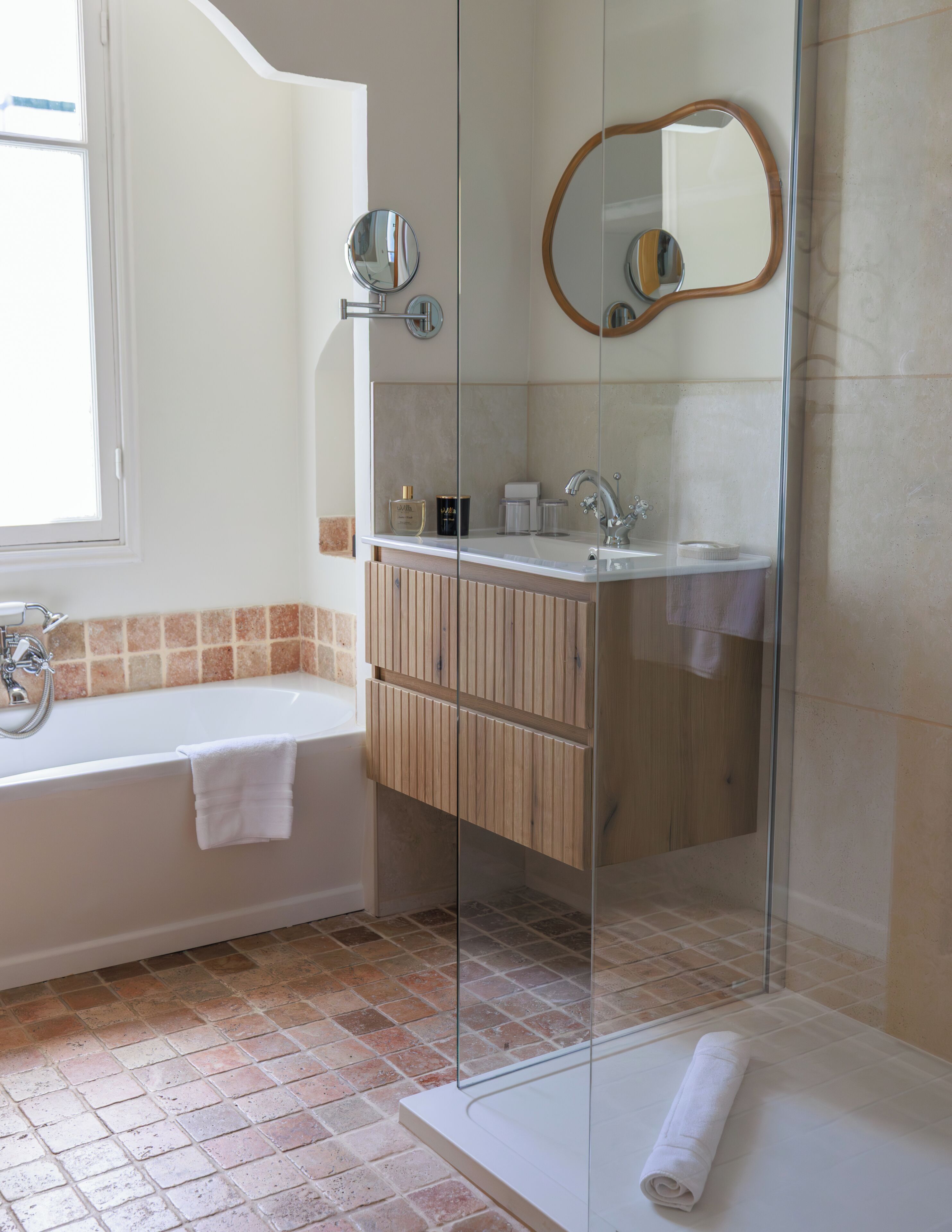 Un baño moderno con bañera, cabina de ducha con paredes de cristal y tocador con espejo.