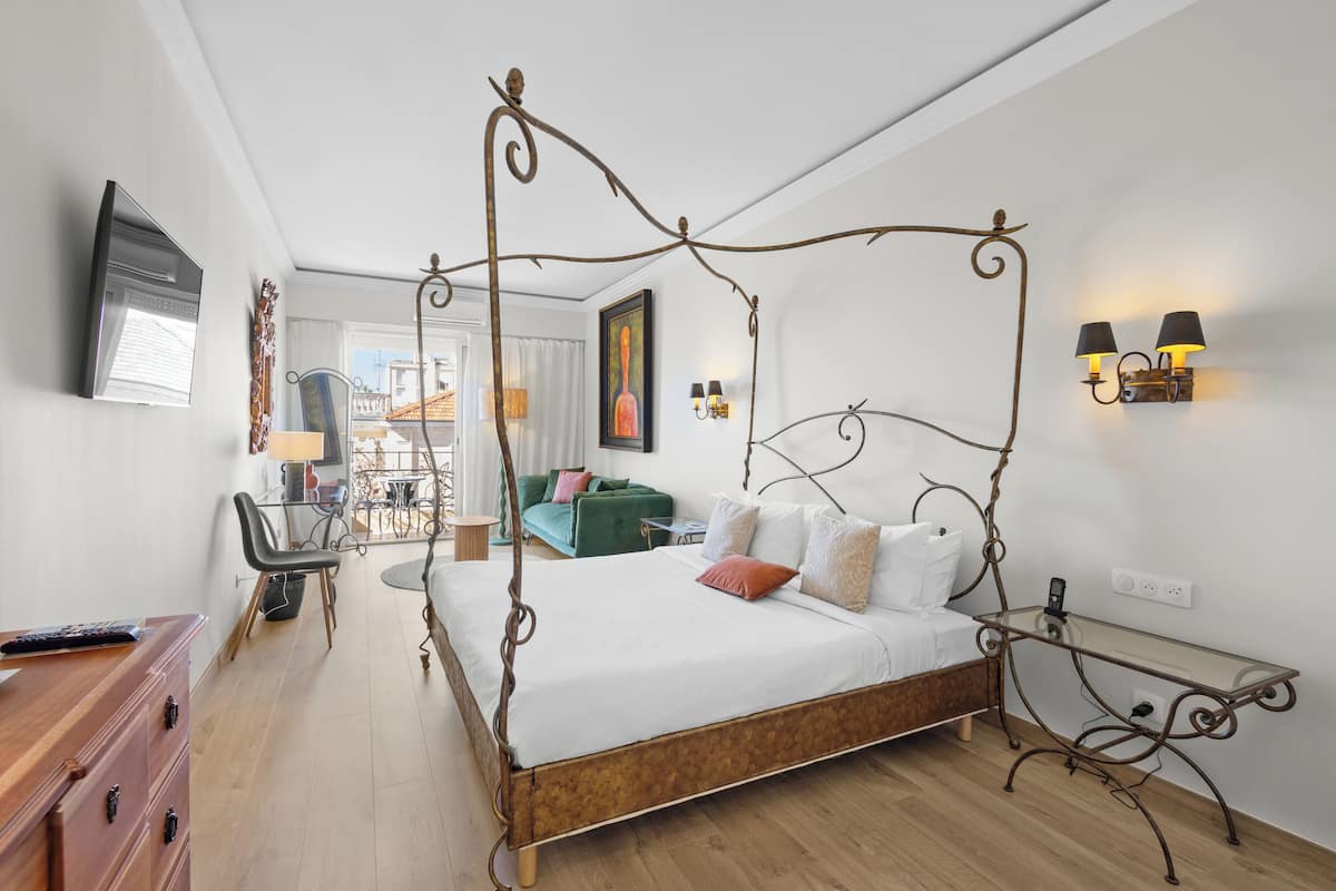 Une chambre moderne avec un lit à baldaquin, un bureau avec une chaise, une télévision et un balcon avec vue.