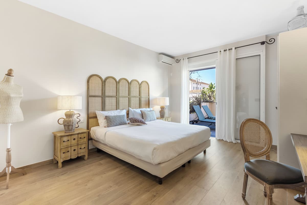 Une chambre avec un grand lit, des tables de chevet, une chaise et une vue sur l’extérieur.
