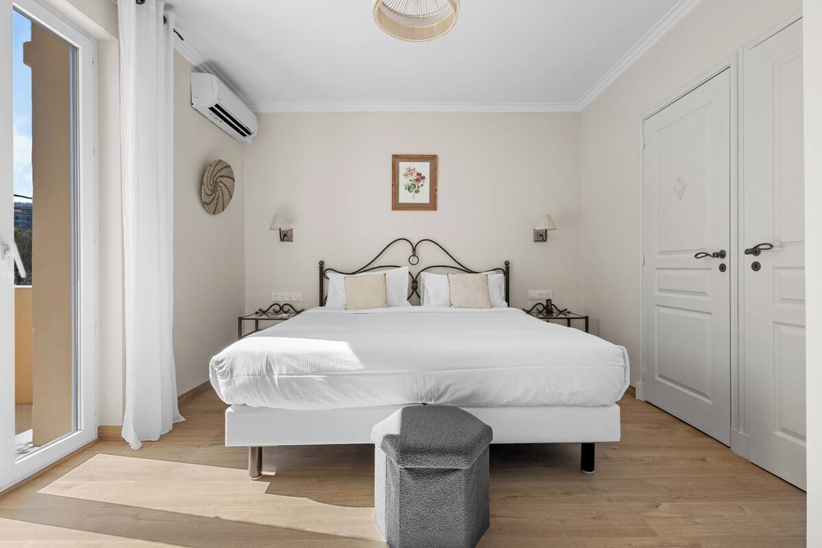 Une chambre à coucher avec un lit, des tables de chevet, une armoire et une fenêtre avec des rideaux.