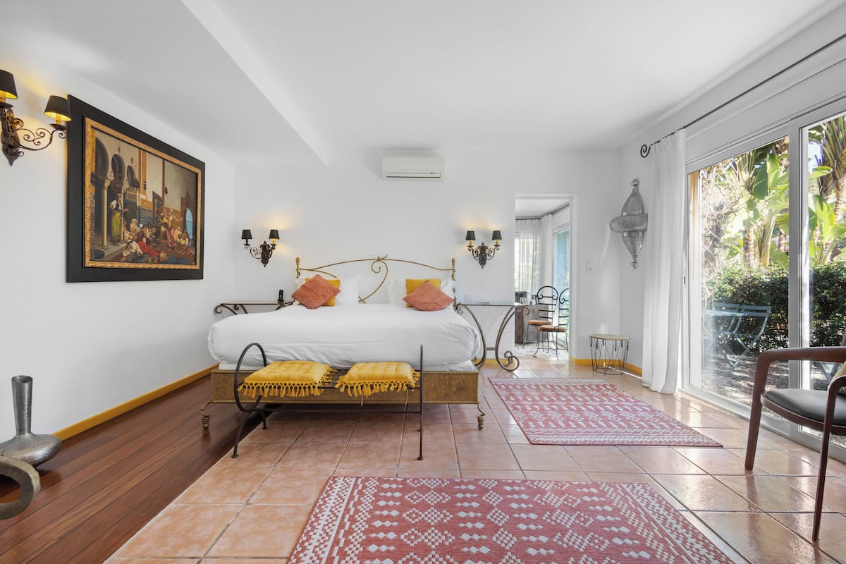 Une chambre à coucher avec un lit, un tableau, une fenêtre et une vue sur l’extérieur.